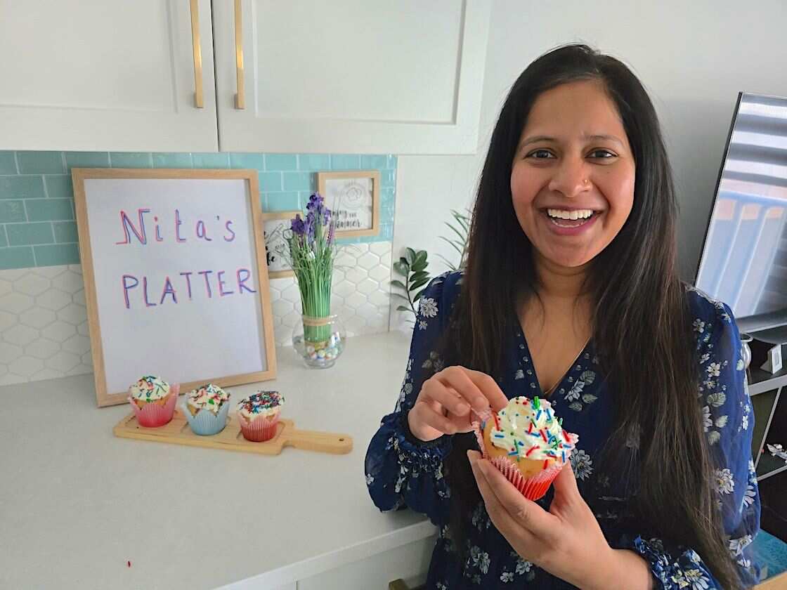 Nita showing her cup cakes in the kitchen setting.