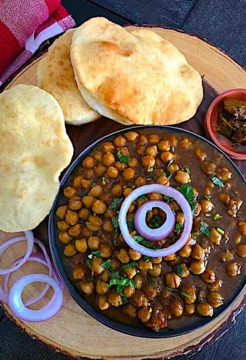 Chole Bhature platter with spicy chickpea curry, fluffy bhature, onions, and pickle.