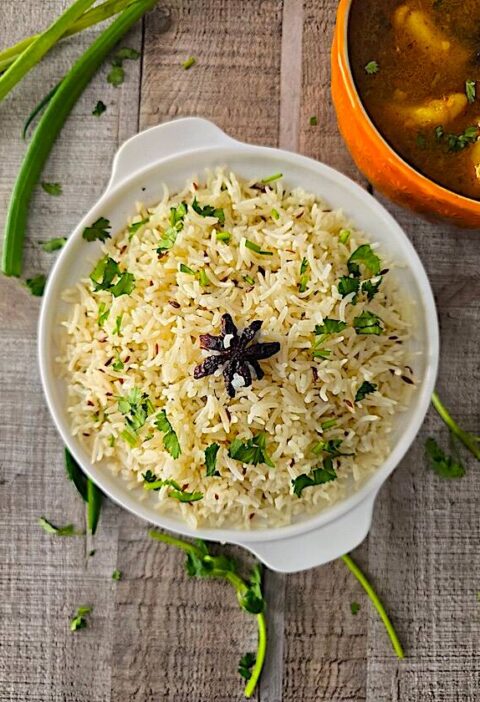 Fluffy Jeera Rice served with a side of flavorful Aloo Curry, garnished with fresh coriander.