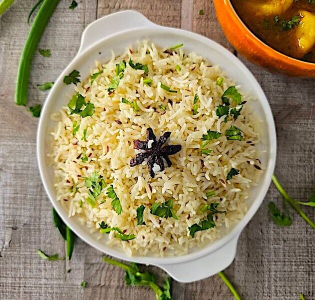 Fluffy Jeera Rice served with a side of flavorful Aloo Curry, garnished with fresh coriander.