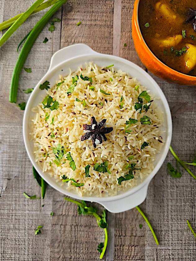 Fluffy Jeera Rice served with a side of flavorful Aloo Curry, garnished with fresh coriander.