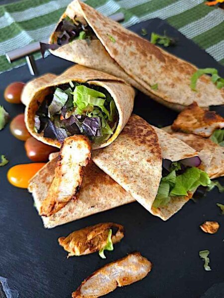 Close-up of a freshly made chicken shawarma wrap filled with grilled chicken, fresh vegetables, and creamy sauces, ready to be served.