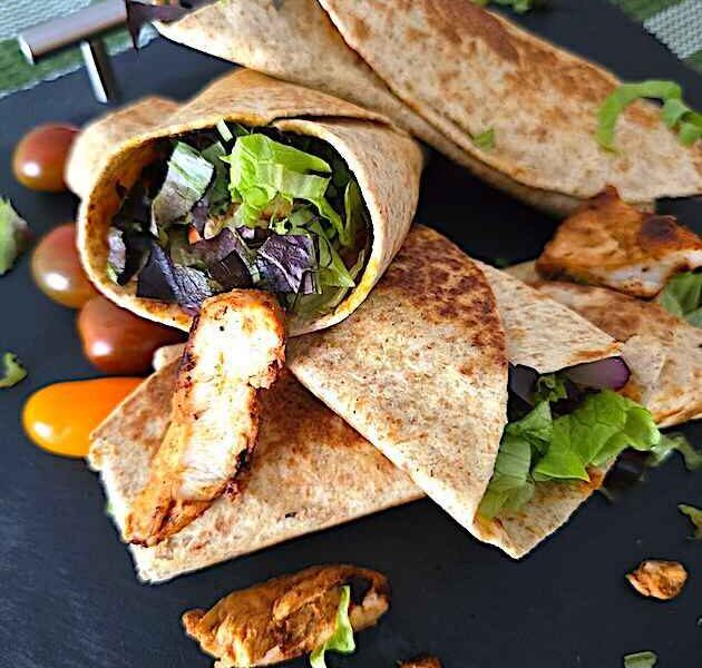 Close-up of a freshly made chicken shawarma wrap filled with grilled chicken, fresh vegetables, and creamy sauces, ready to be served.