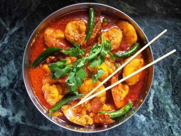 Prawn curry garnished with green chillies and cilantro leaves